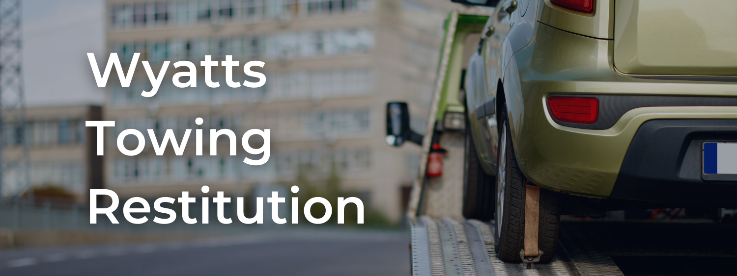 Vehicle on tow truck with text, Wyatts Towing Restitution.