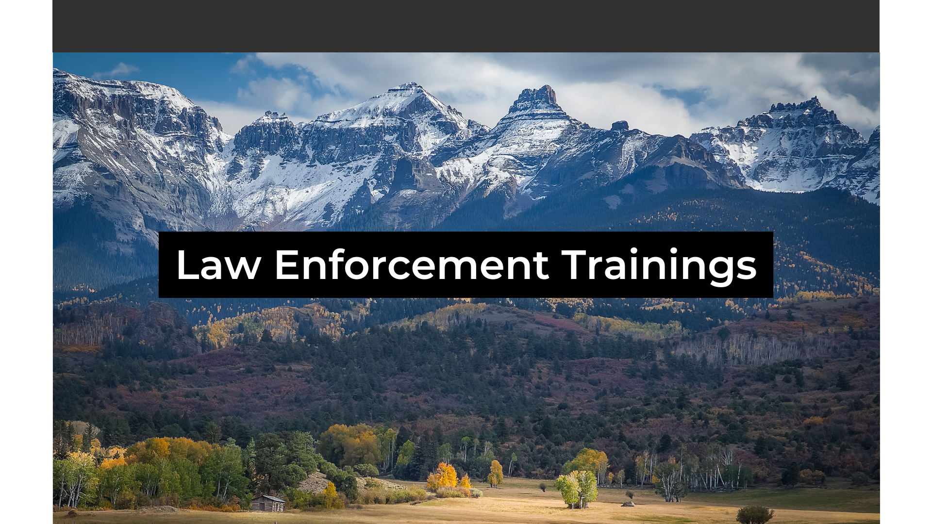 Snowcapped Rocky Mountains with a field below with the changing fall colors