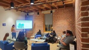 adults sit around a screen with a brick wall in the background